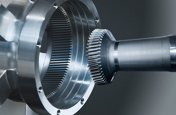 Close-up of a metal gear assembly in which a shaft with a spur gear is inserted into a component with internal teeth.